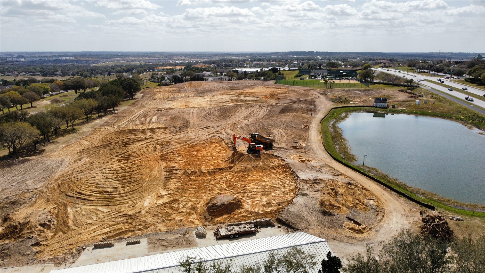 Excavator and haul vehicle working across a large graded site